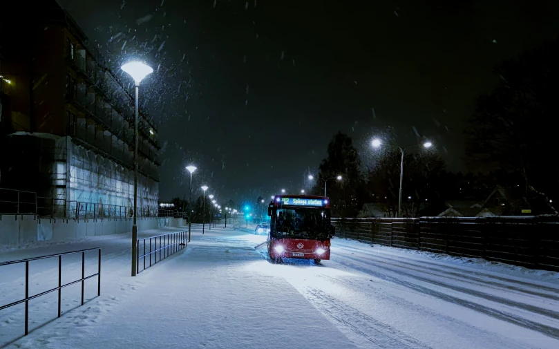 a bus is driving down the road at night in the snow