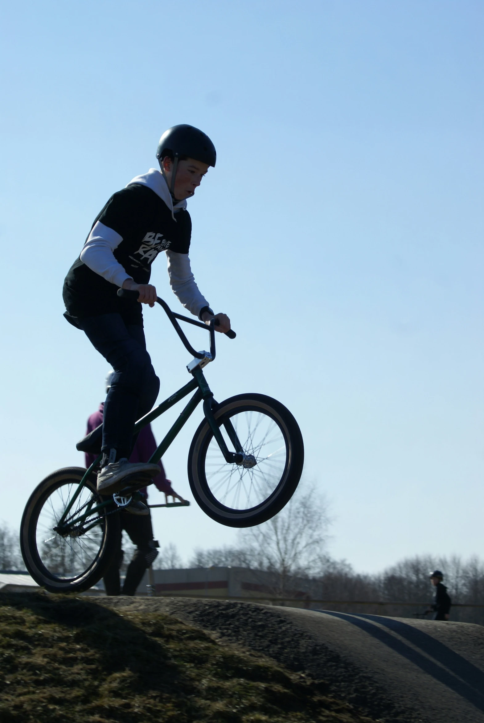 man doing trick on bicycle with little girl riding nearby