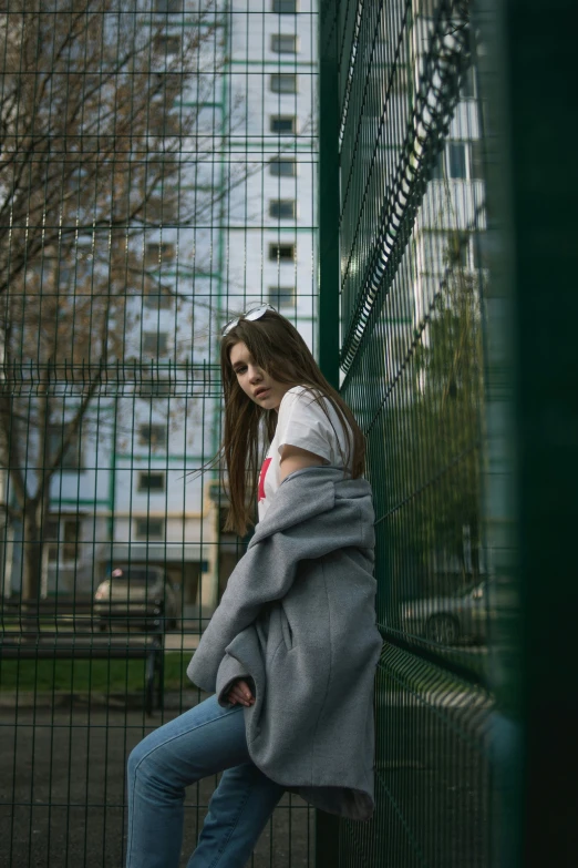 a girl leans against a green fence