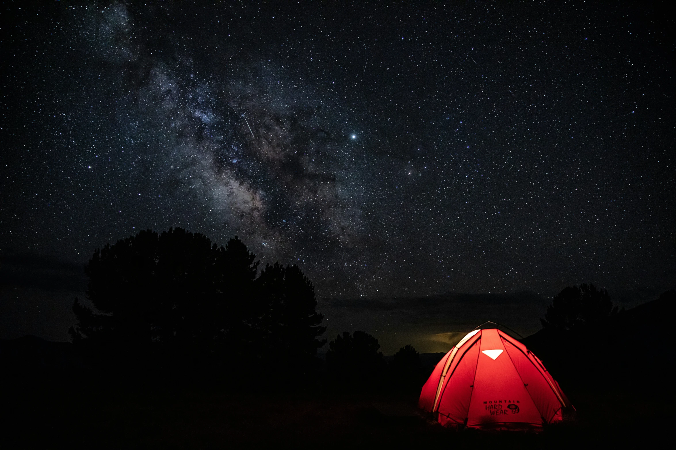 a red tent is in the dark, with stars on the sky