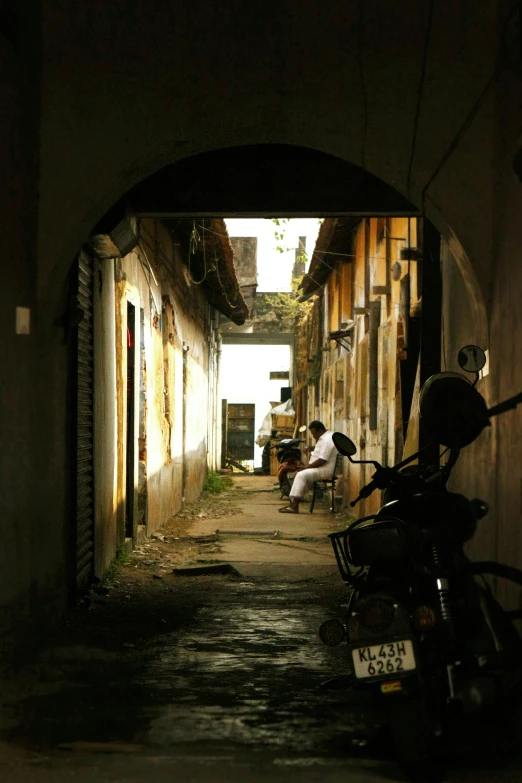 two men sit on a bicycle in an alley