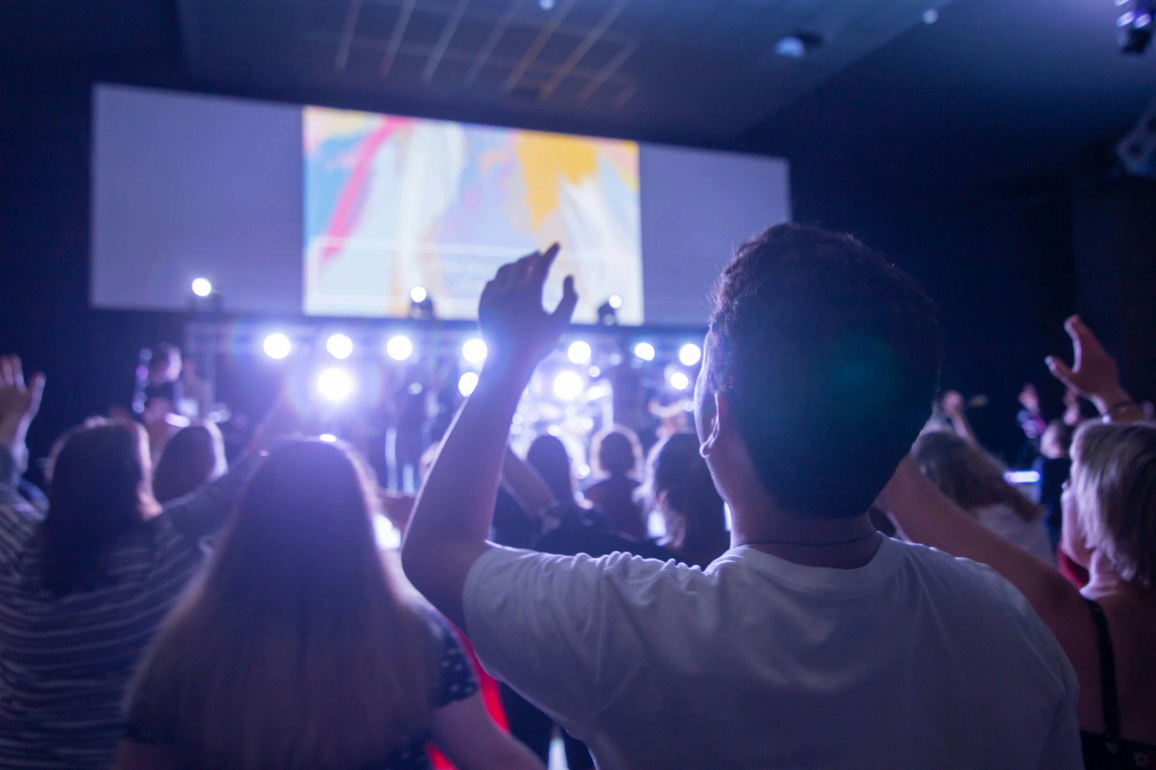 a crowd of people in a large room with their arms up