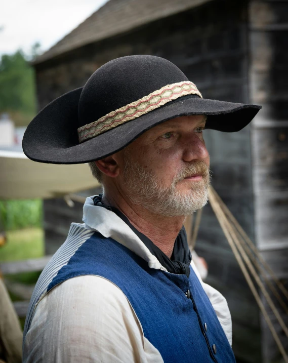 a man is wearing a hat and standing outdoors