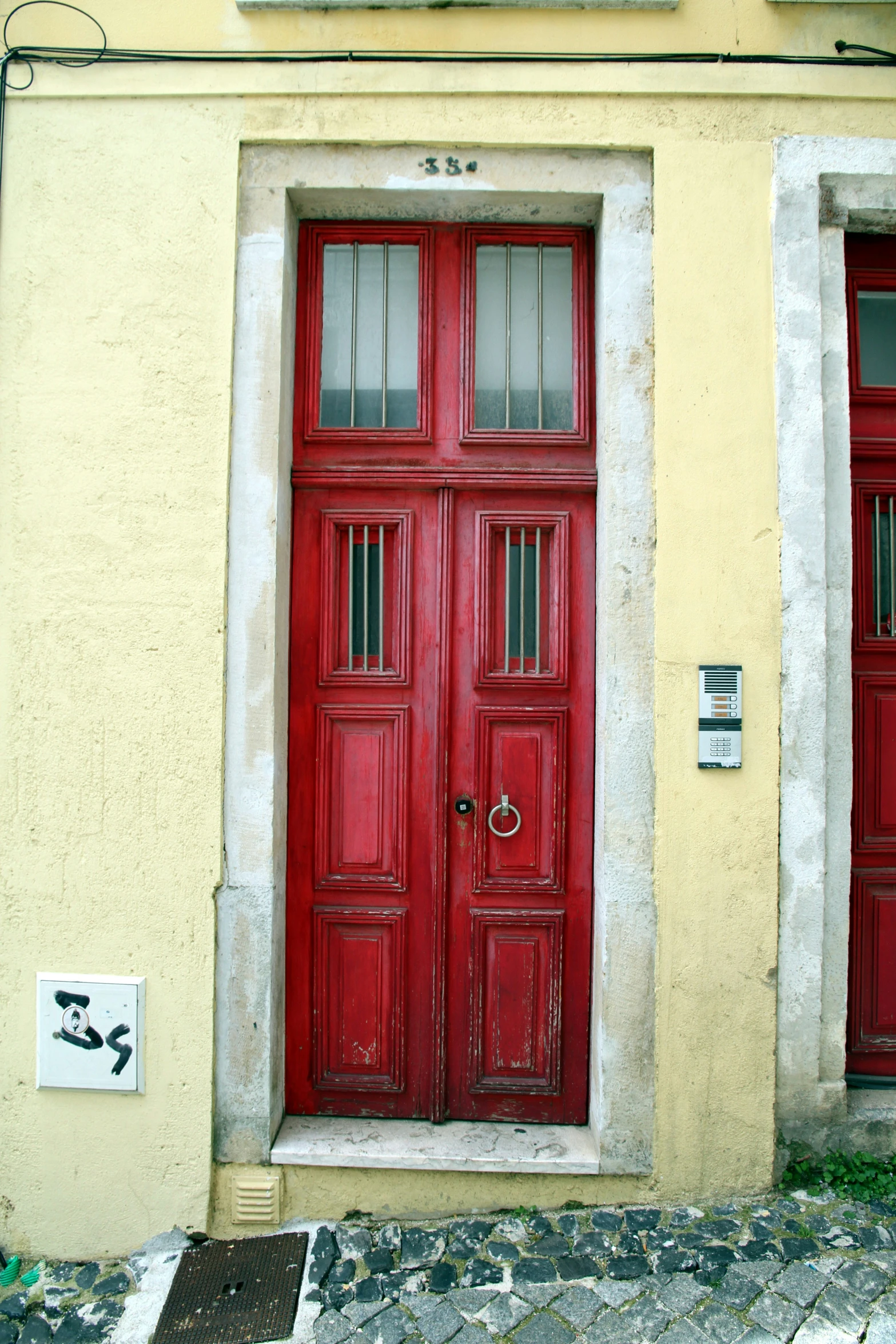 a red door on a tan building with a clock above