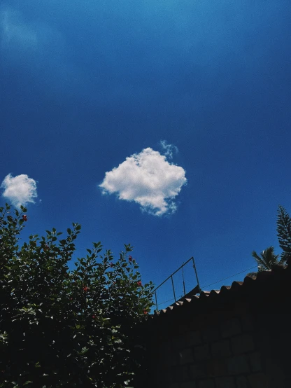 a white cloud in the blue sky on top of a house