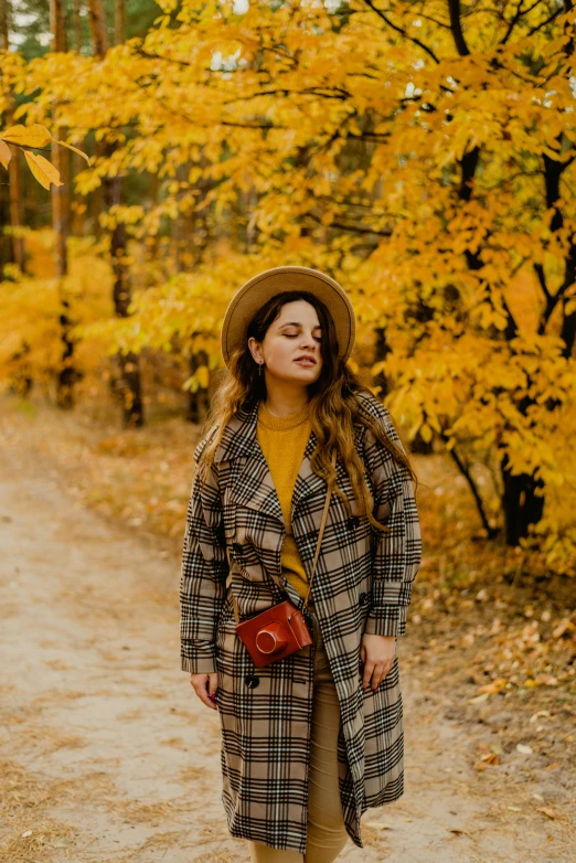 a young lady wearing a hat, trench coat and holding a red purse