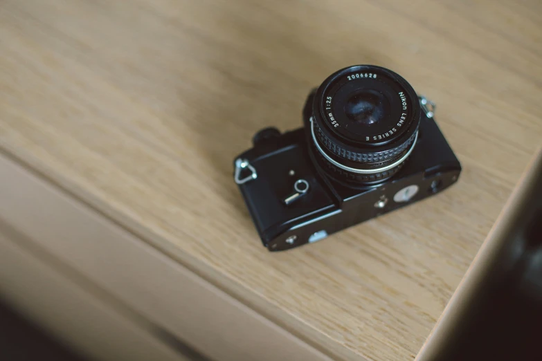 a close up of a black camera on top of a wooden surface