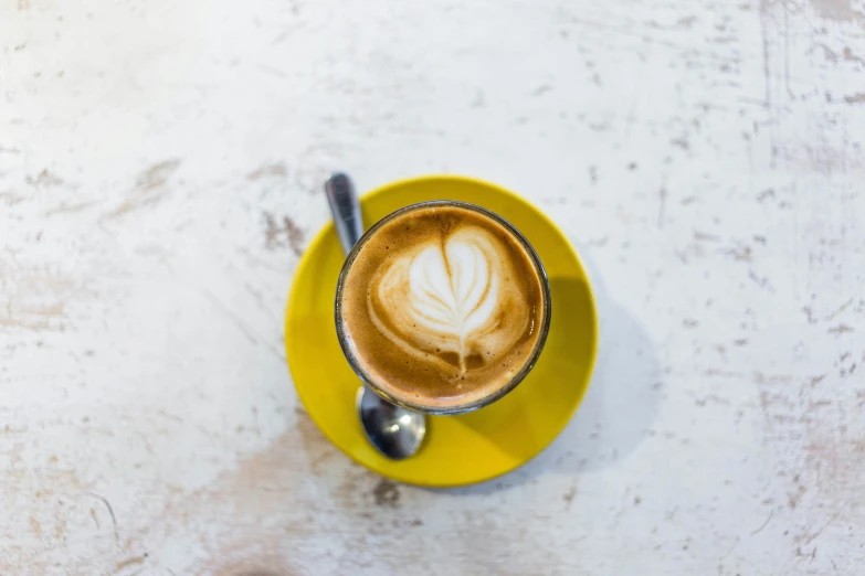 a yellow plate that has a cup of coffee on it