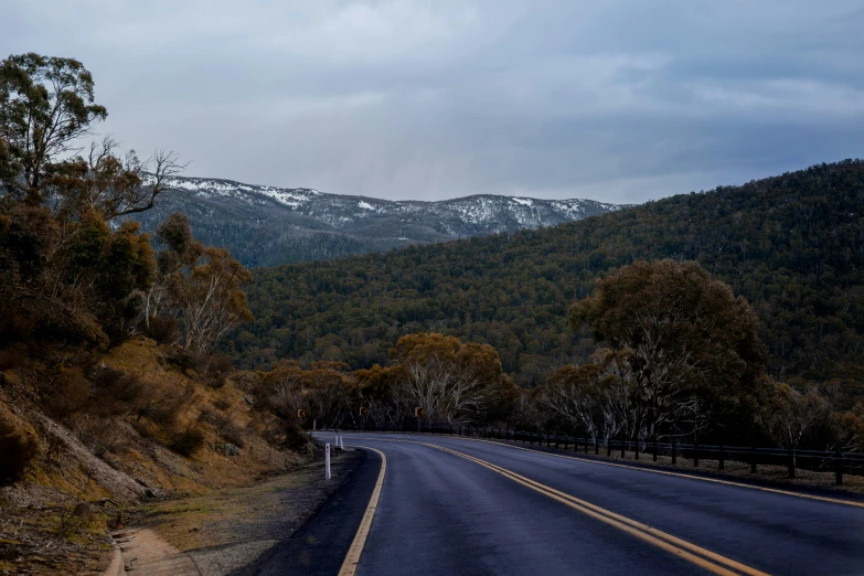 an empty road going through the mountains covered in snow