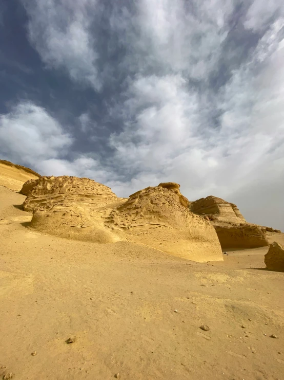 a large rock formation in the desert under cloudy skies