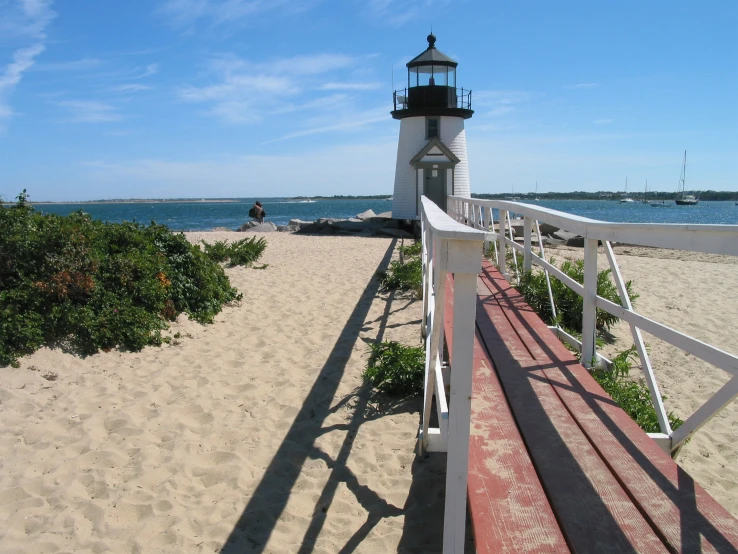 a lighthouse sits over a path at the end of the beach