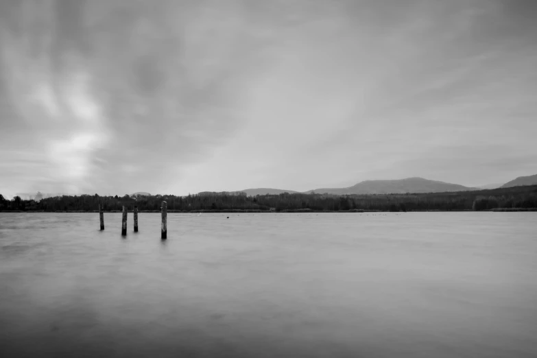 a lake with four posts sticking out from the water