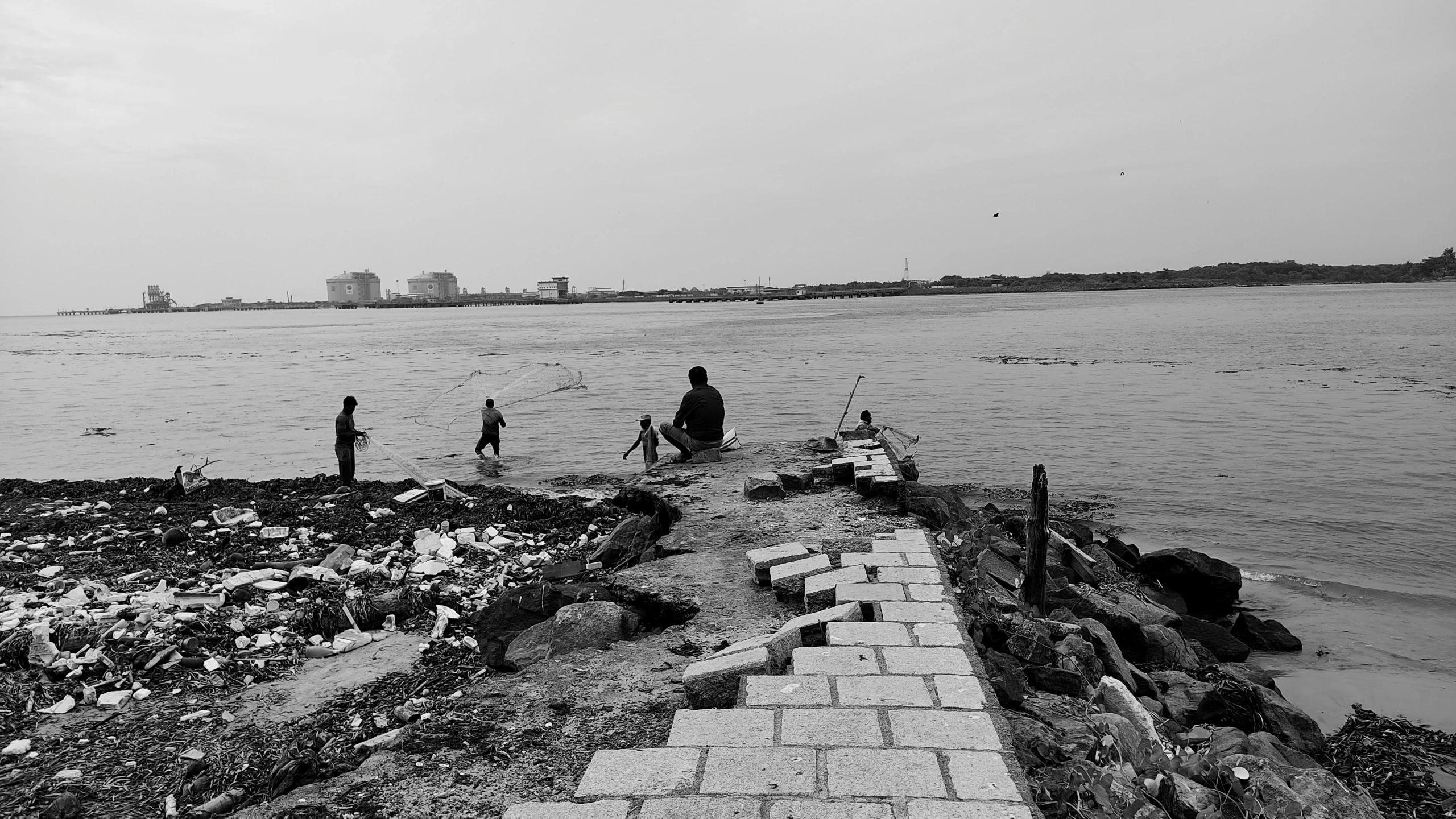 a black and white image shows children on shore next to the ocean