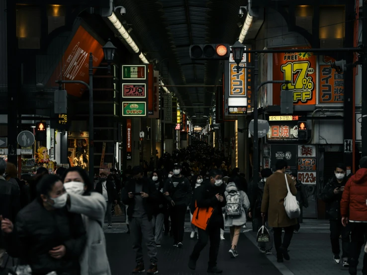 a crowd of people walking down a street next to tall buildings