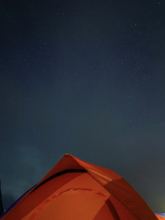 a camp ground with a light tent in the foreground and a couple tents on the other side