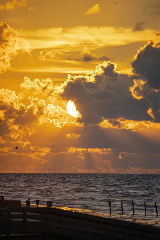 the sun setting on a cloudy day at the beach