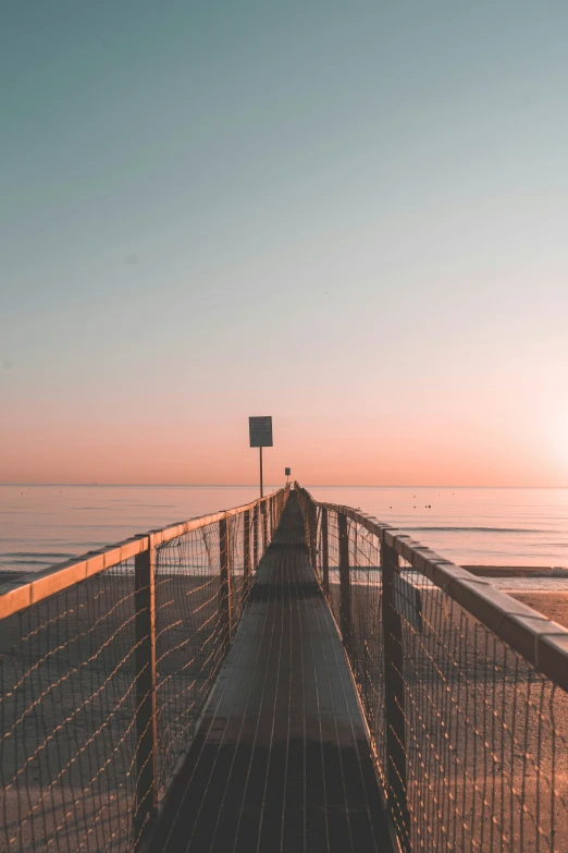 a person sitting on top of a fence next to the ocean