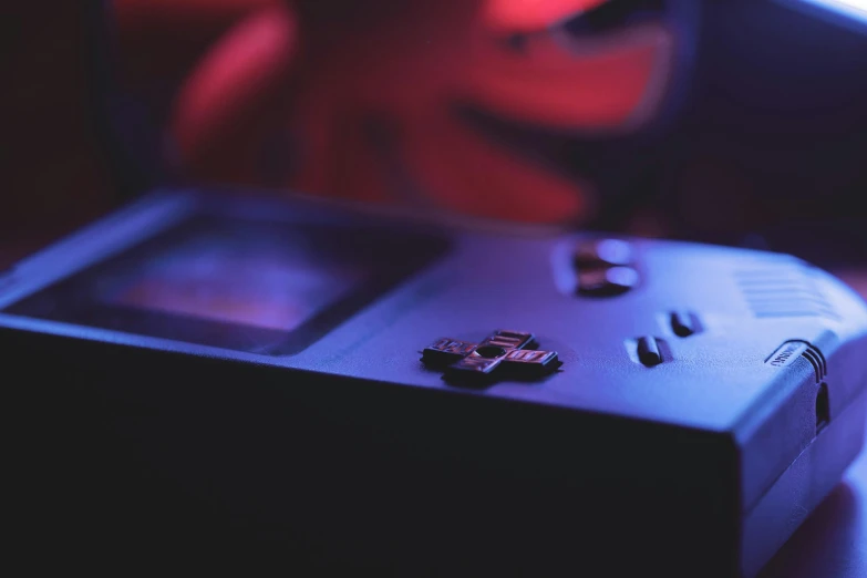 a small black game console next to a red stuffed animal