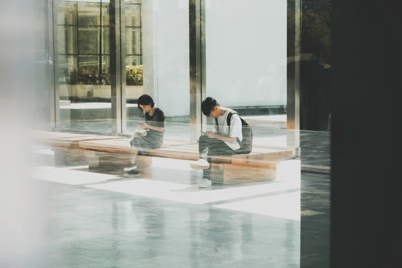 two people sitting on benches looking at their phones