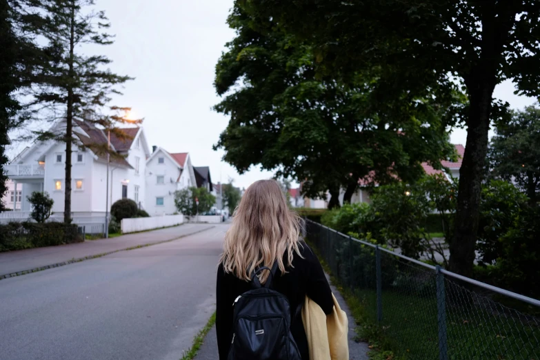 a woman carrying luggage down a street in front of white houses