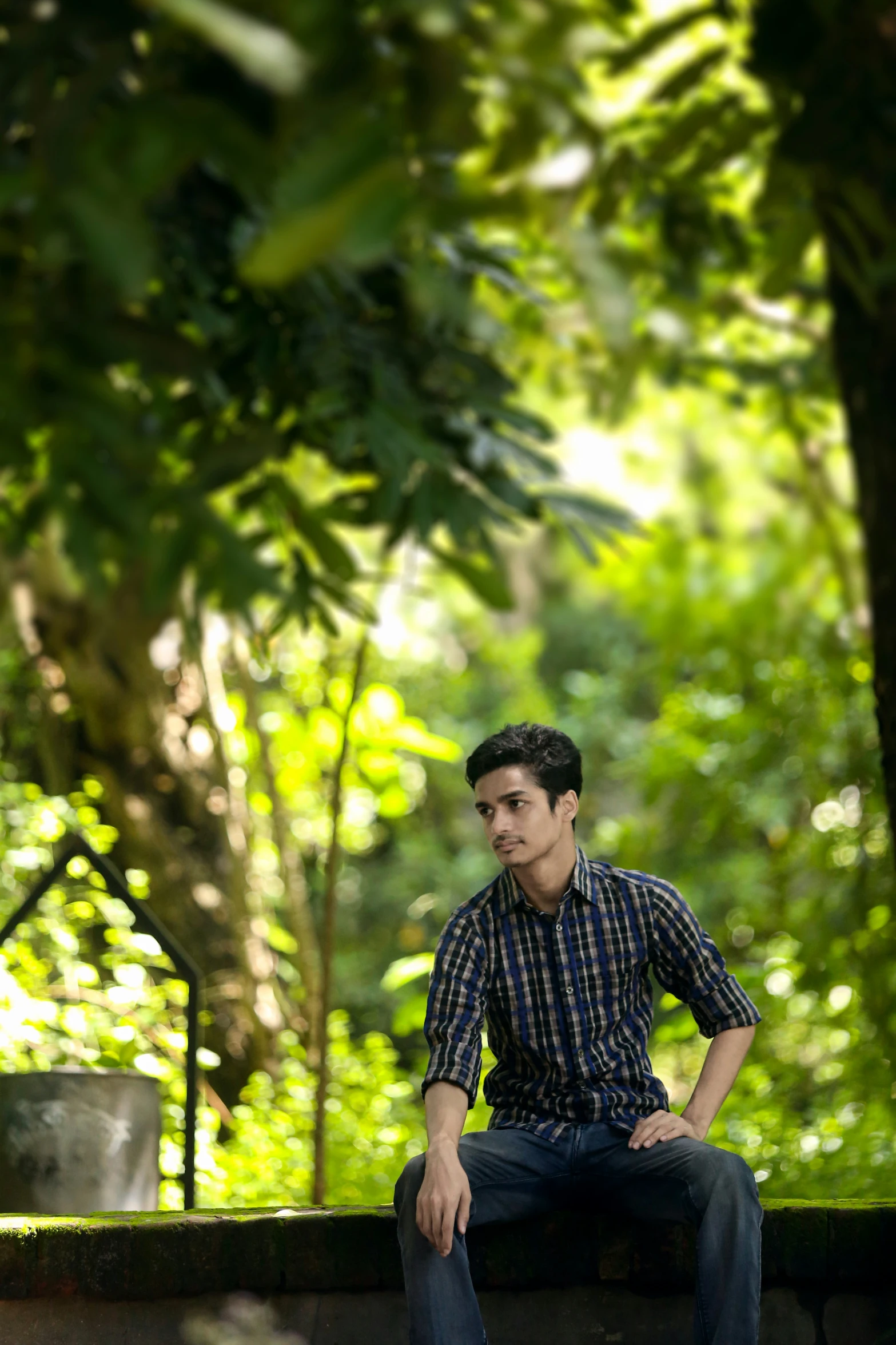 a guy sitting on a wall with trees in the background