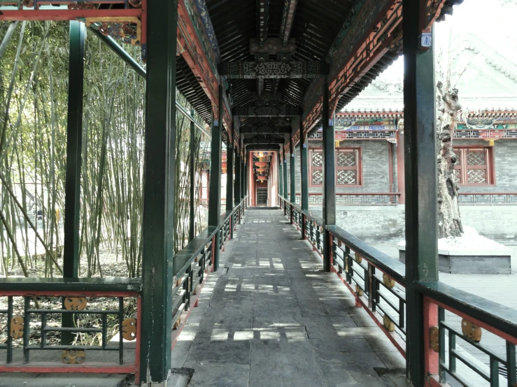 a hallway with wooden pillars and lots of bamboo