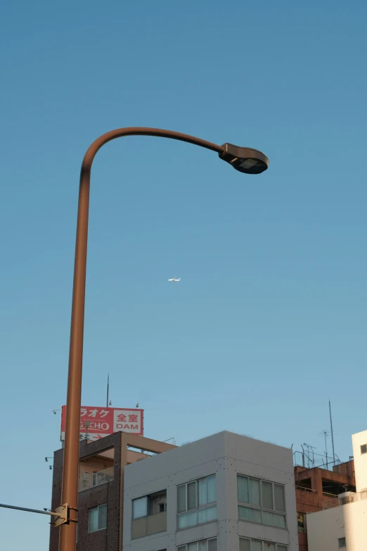 a street light against the sky with buildings below it