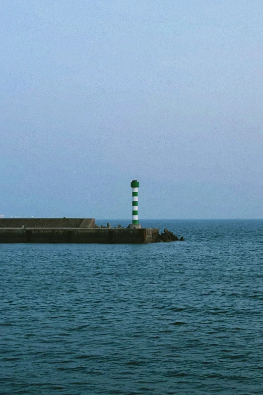 a green and white lighthouse sitting on top of water