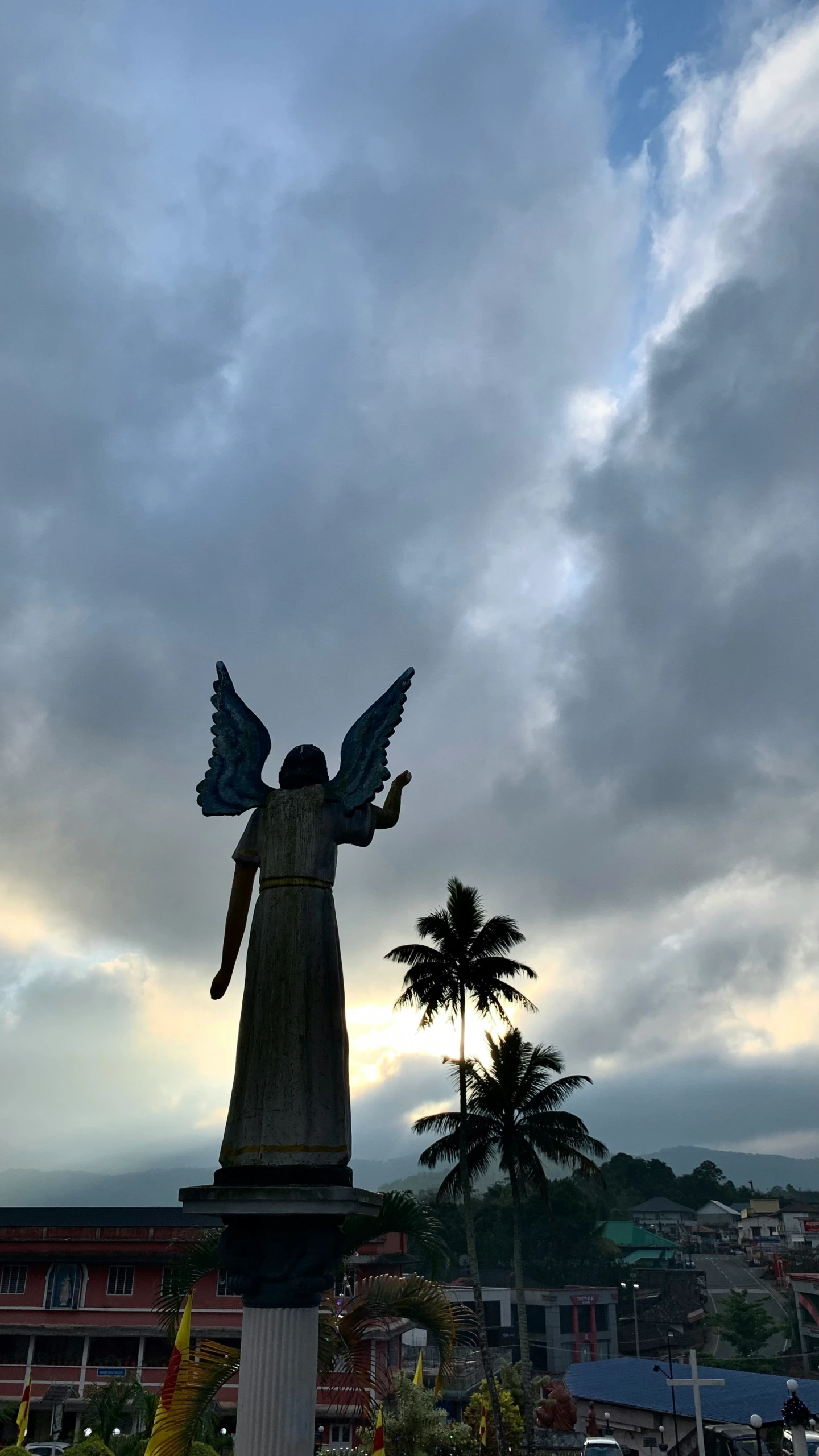 the statue is near a palm tree in front of some buildings