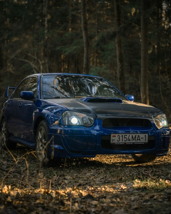 a blue car parked in the woods by itself