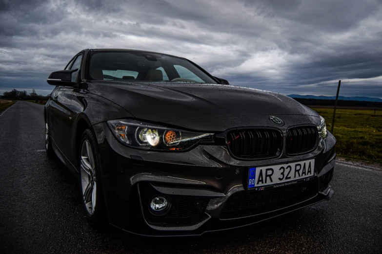 a bmw sits parked on the street as dark clouds loom in the sky