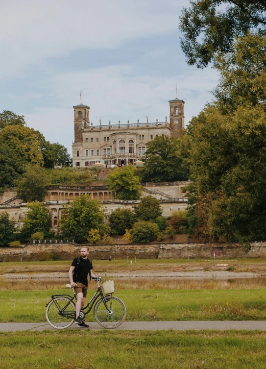 there is a man that is riding a bike by the grass