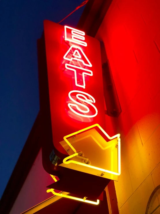 a neon sign is on the corner of the street