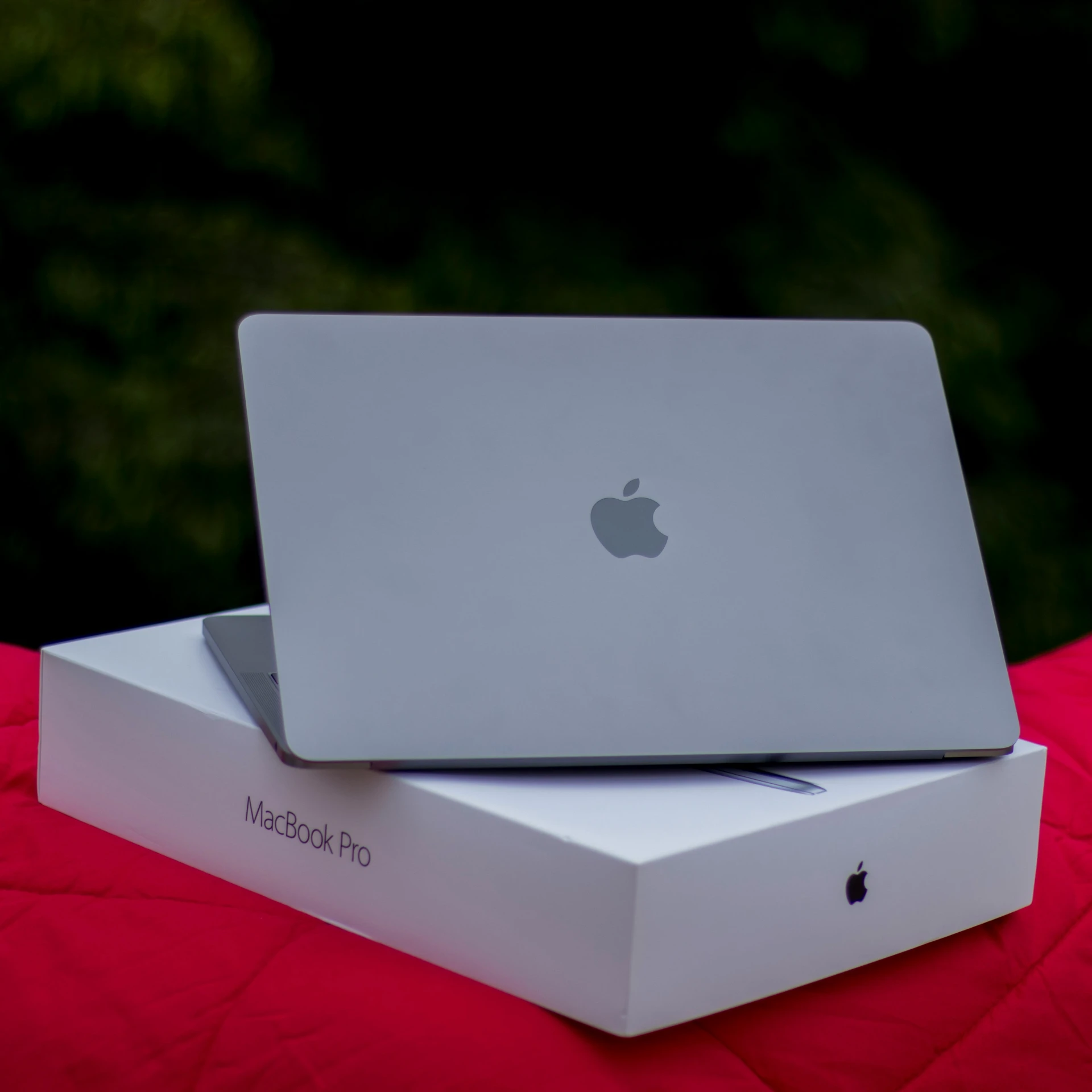 the two apple laptops are sitting on a red cover