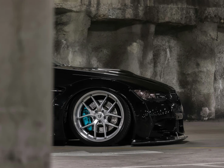 a black sports car is sitting against a stone wall