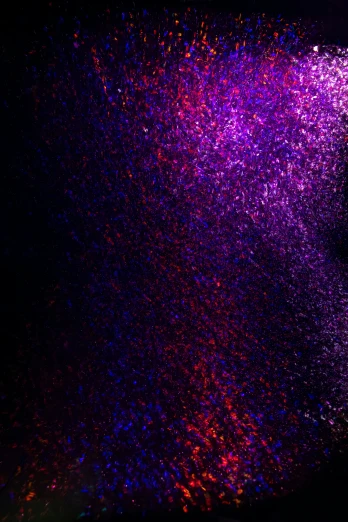 a dark background has a purple and red speckle