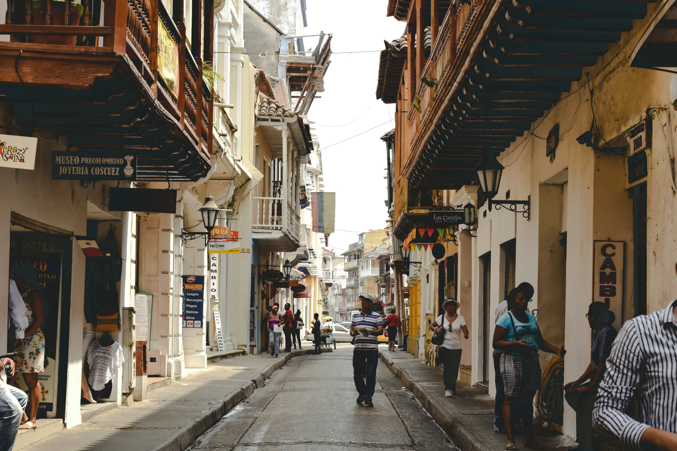 a narrow street in a city with people walking through it