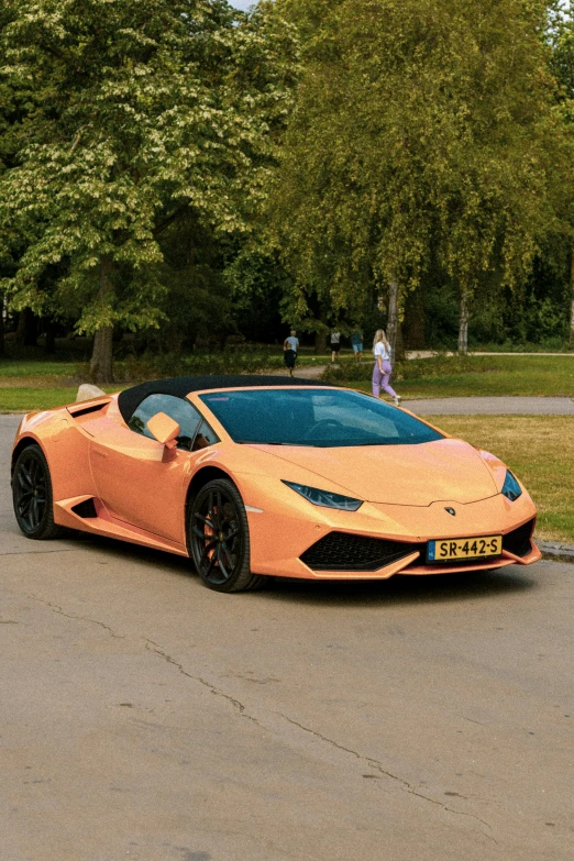 a very nice orange car in front of some people