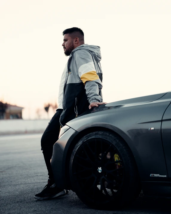a man sitting on the hood of a sports car