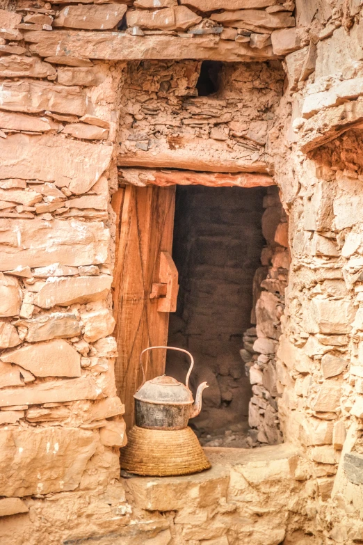 a rustic looking pot sits next to a brick wall