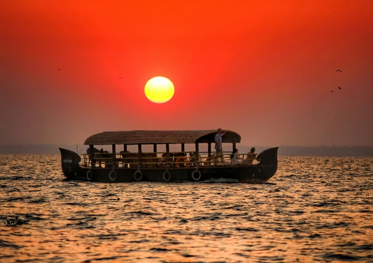 a boat is floating in the water as the sun sets