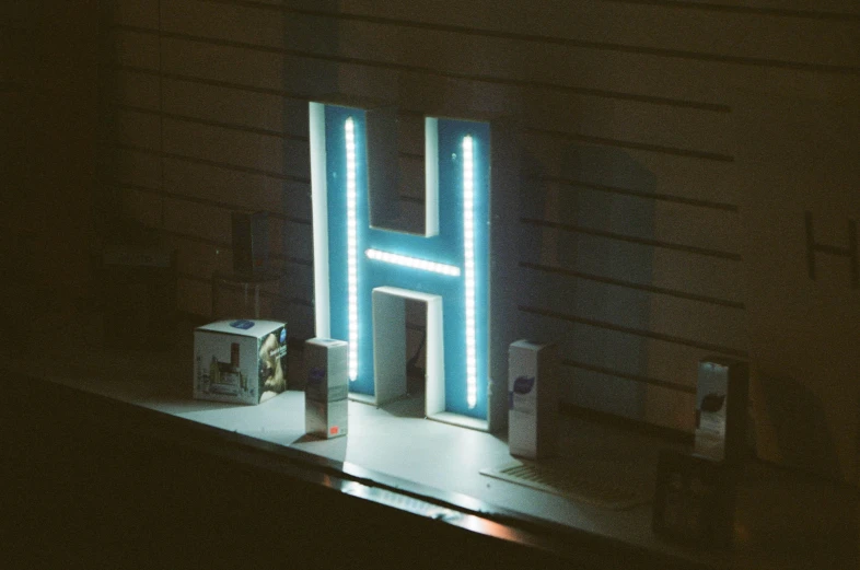 a lit up neon letter in front of a dark wall