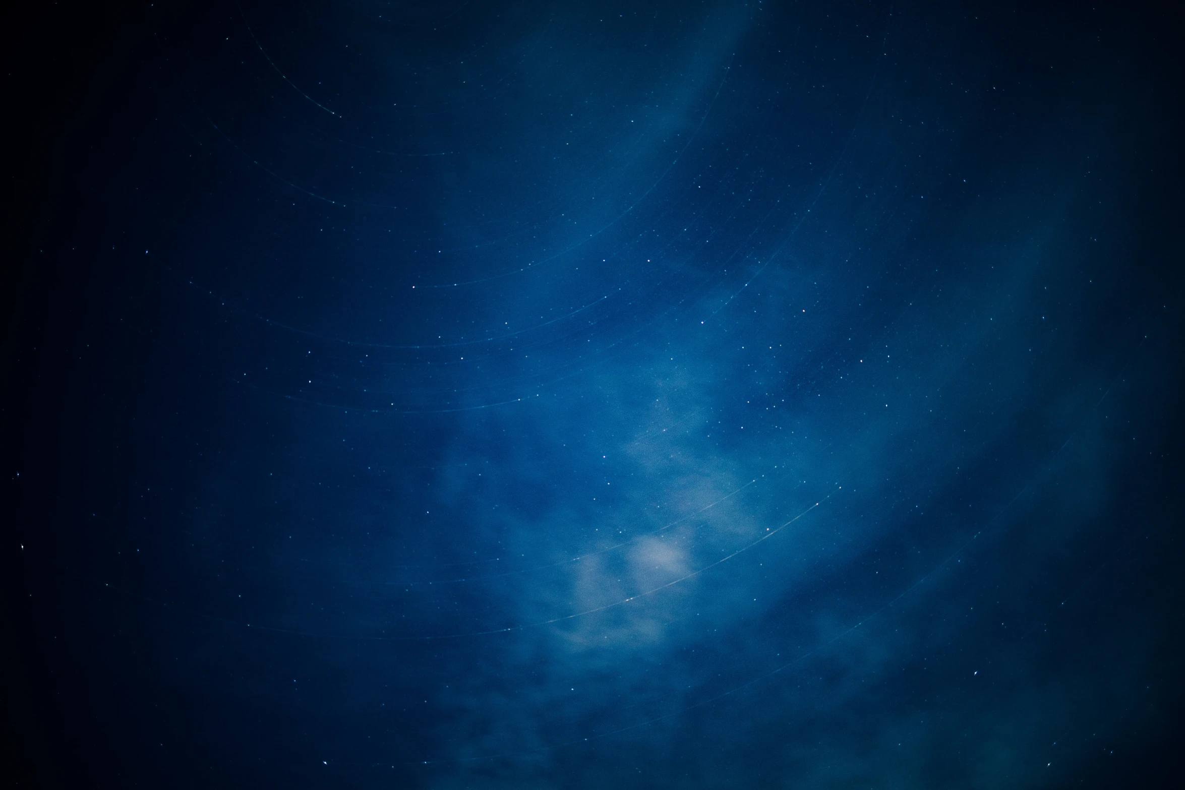 stars streak across the night sky in front of a moon