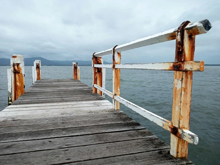 a pier stretching out into the water from under a cloudy sky