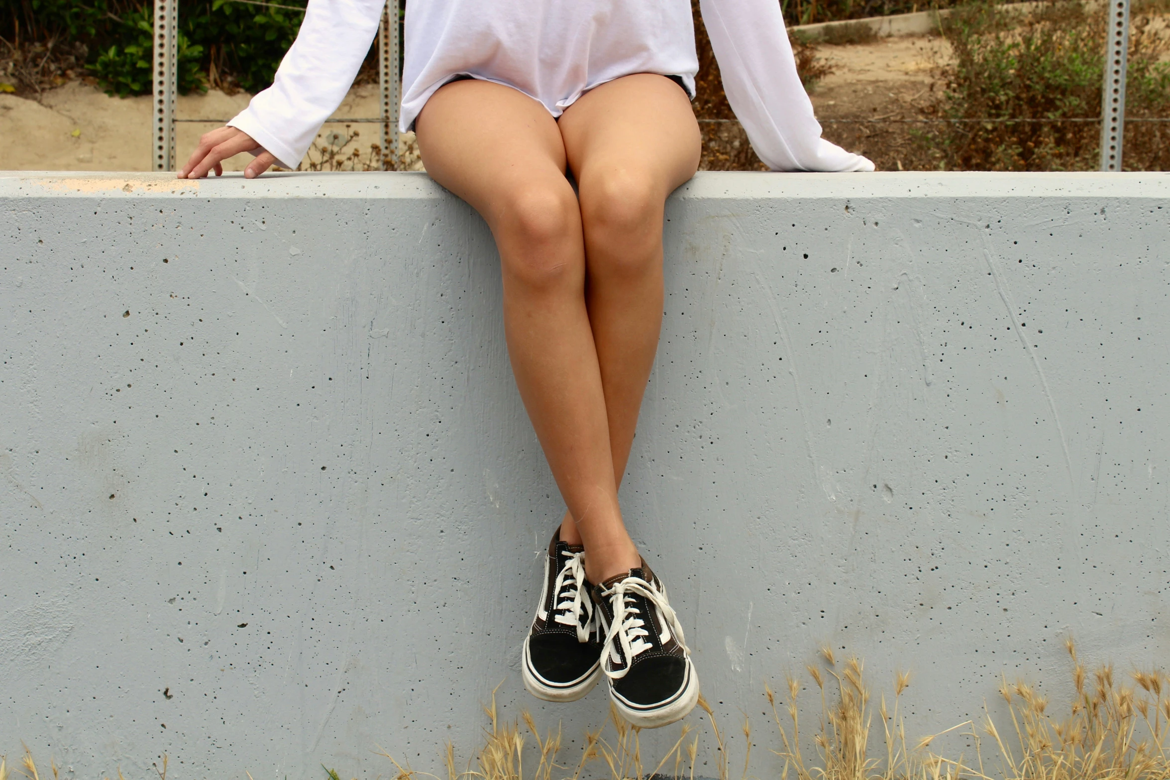 a woman in shorts with her legs stretched out and a black sneaker is on a ledge