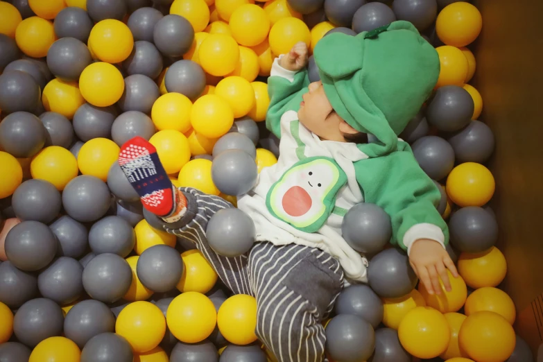 a baby boy with his feet propped on balls in a toy play room