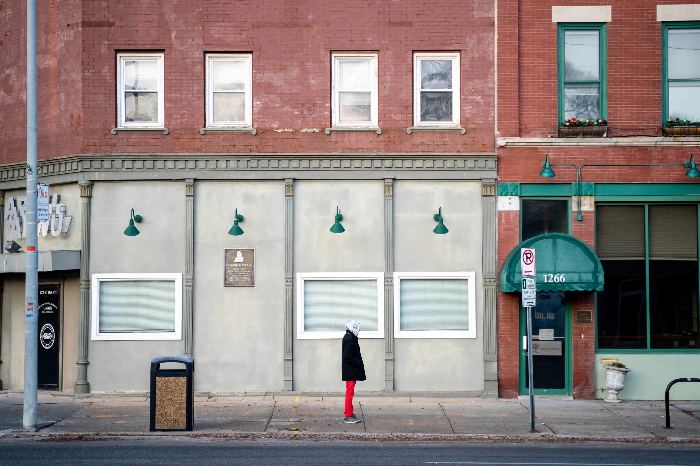 a brick building with large windows and a sign for a store on the sidewalk