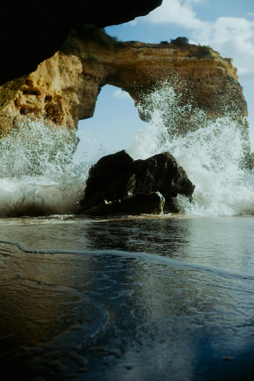 a rock sticking out from the water that is crashing