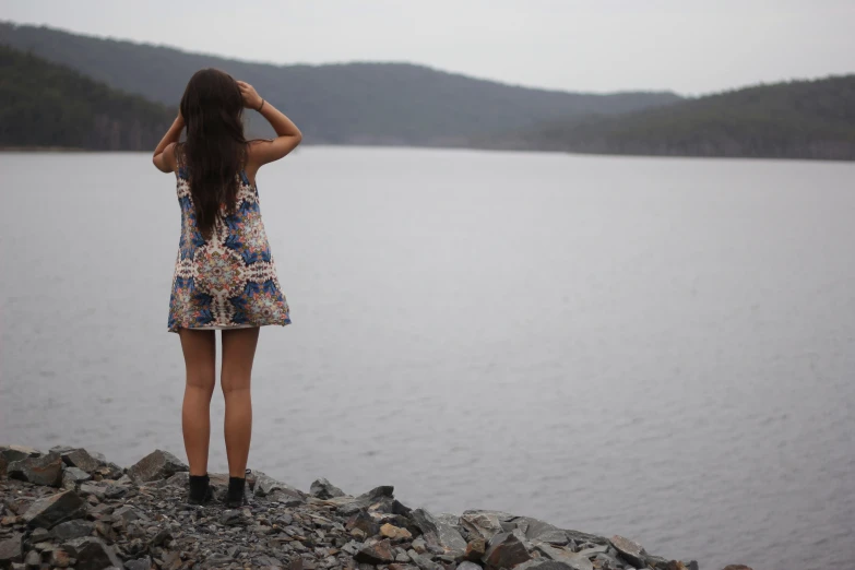 a woman in a short dress looks out at a lake