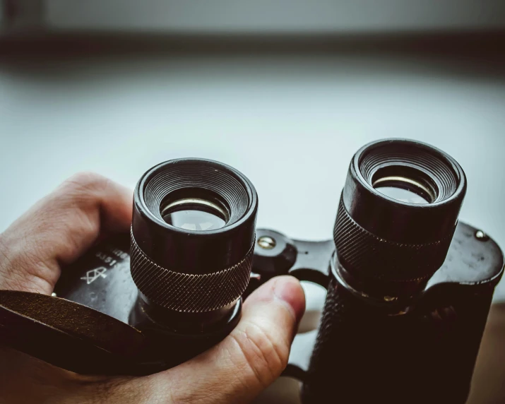 two hands are holding binoculars over a camera